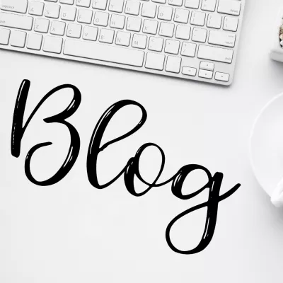 Eine Tasse Kaffee und eine Tastatur auf einem Schreibtisch, und das Wort "Blog" in großen Buchstaben.