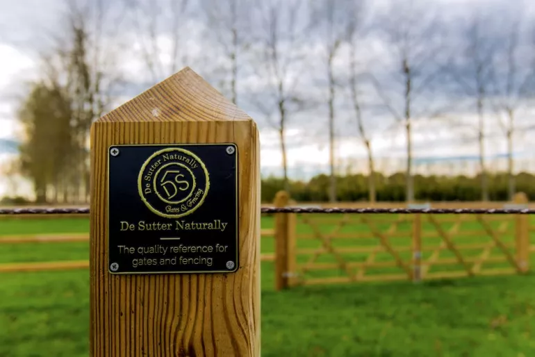 Ein quadratischer Holzpfosten und ein doppeltes hölzernes Feldtor
