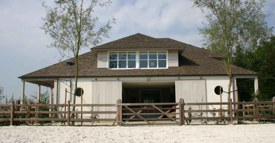 Ein hölzernes Feldtor, das an einem Holzzaun mit drei Stäben und quadratischen Pfosten befestigt ist